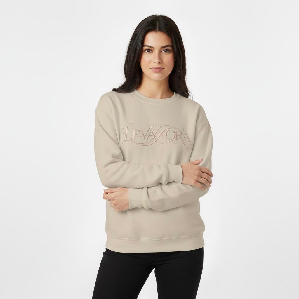 Woman wearing a Sand sweatshirt with a 'LEVANORA' logo on a plain background