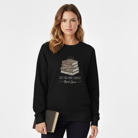 Woman wearing a Black sweatshirt with a book-themed design, holding a book.